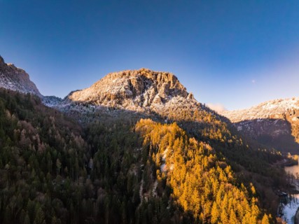 Sunrise illuminates the snow-covered peak and autumnal forest, Bad Reichenhall, Bavaria, Germany,