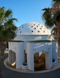 White, decorative domed architecture surrounded by palm trees under a clear sky, thermal springs,