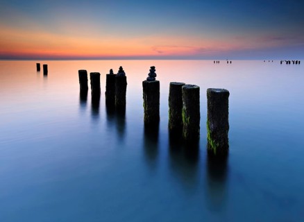 Stone pyramids on old groynes with algae in the water on the beach of the Baltic Sea, long exposure