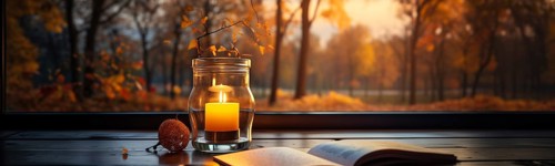 Warm and inviting lit candle resting near an open book on wood window sill in A fall setting.