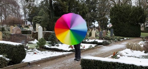 Man with colourful umbrella in grey weather between graves, Riesa cemetery, Saxony, Germany, Europe