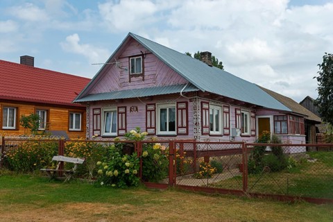 Wooden house with red roof in a rural setting, surrounded by garden and flowers, Wojszki,