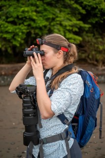Tourist looking through binoculars, with headlamp and camera in the rainforest, Corcovado National