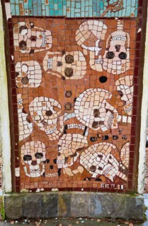 Artistic mosaic with skulls in brown colours and square patterns, Jama pod Krenom, remembrance of