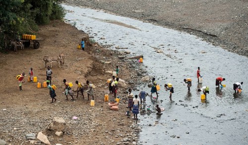 Women and girls fetch water in plastic canisters from a river near the road from Arba Minch to