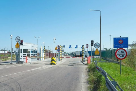 Customs station with open barrier and traffic signs on a sunny day, border from Poland to Ukraine,