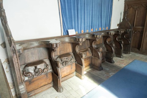Carved decorated wooden misericord seats in church at Framsden, Suffolk, England, UK