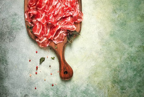 Prosciutto on a cutting board, top view, appetizer, breakfast, spices and herbs