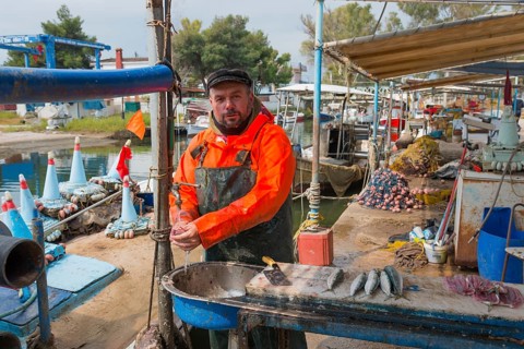 Fishermen standing in the harbour, dressed in orange, ready to sell fish, busy atmosphere at the