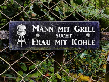 Sign on the fence with the slogan Man with barbecue seeks woman with coal, Traben-Trarbach, Middle