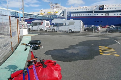 Several motorhomes are parked on a ferry car park, with a large ferry in the background, Transport,
