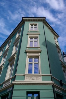 Historic building with mint facade and cream-coloured window frames under a clear blue sky with