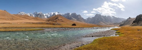 Mountain landscape with yellow meadows, Kol Suu River and mountain peaks with glaciers, Keltan