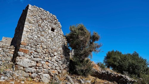 An abandoned ruin with stone walls under a clear blue sky, Flomochori, residential tower village,