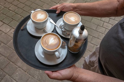 Waiter brings three cappuccinos on a tray to the guest, Bavaria, Germany, Europe