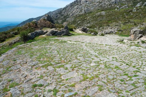 A cobbled path winds through a rocky and green landscape, old Roman road, at the Puerto del Pico,
