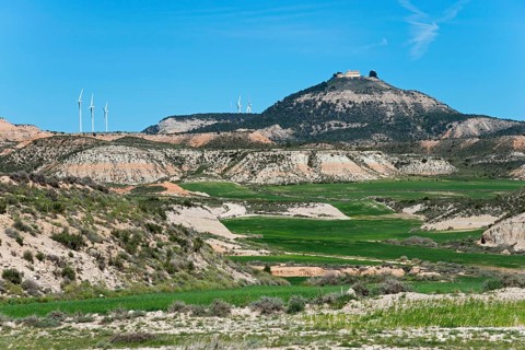 Hills with green fields and wind turbines under a clear blue sky, Bardenas Reales Natural Park,