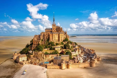 Island abbey majestically enthroned above sandy ground and under a clear sky, Le Mont-Saint-Michel