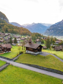 Picturesque Alpine village in a valley surrounded by green hills and majestic mountains, Lake