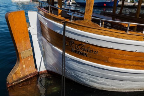 Rudder on docked white painted and varnished wooden boat in harbour in late summer, Sibenik,