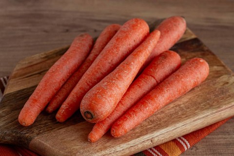 Fresh carrots on a chopping board, wooden table, raw carrots, no people