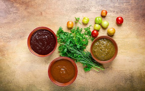 Set of tkemali sauces, three types of tkemali sauce, in ceramic bowls, top view, Georgian cuisine,