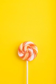 Single lollipop candy on yellow pastel background. copy space, top view, flat lay