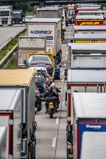 Motorcyclists squeeze past in the middle of the road between vehicles, in a 9 km long traffic jam