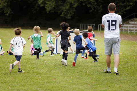 Volunteer coach trains children on the football pitch, Bonn, 19.06.2024