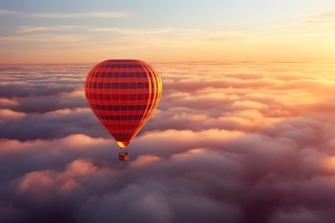 Colorful hot air balloon floats over a sea of clouds at sunset at sunset with orange and blue skies
