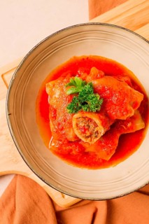 Stuffed cabbage rolls, with minced meat, in tomato sauce, on a beige background, food and drink,