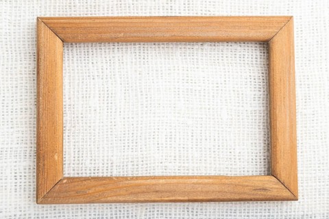 Wooden frame on smooth white linen tissue. Top view, flat lay, natural textile background and