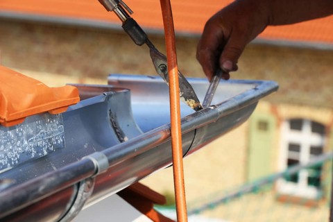 Roofer doing tinsmith work on a gutter