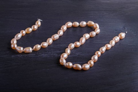 Caramel colored pearl beads on a black background. top view, close up