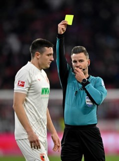 Referee Referee Daniel Schlager shows Keven Schlotterbeck FC Augsburg FCA (31) yellow card yellow