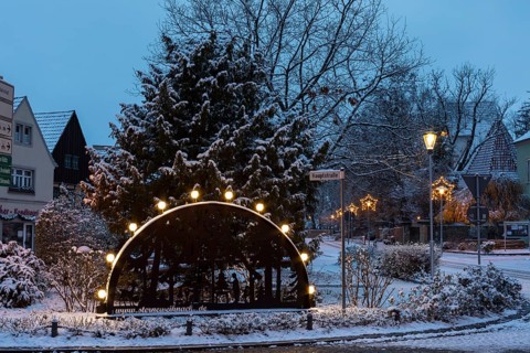 Candle arch on the main street, snow-covered and at dusk, in the background the old church, Coswig,