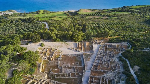 Drone shot, first morning light, aerial view of ancient ruins near the coast, surrounded by green