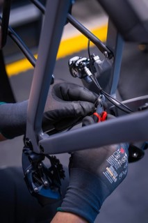 Gloved hands with pliers during bicycle assembly, Waldbike Manufaktur, bicycle workshop, Calw,