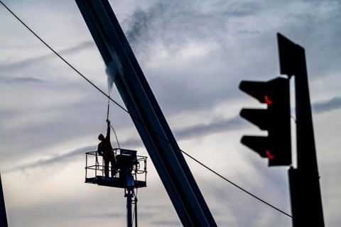 Worker cleans a bridge pier with a high-pressure cleaner on a cherry picker at the Erasmus Bridge