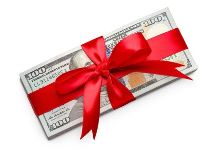 Stack of one hundred dollard bills wrapped in a red ribbon and bow isolated on a white background