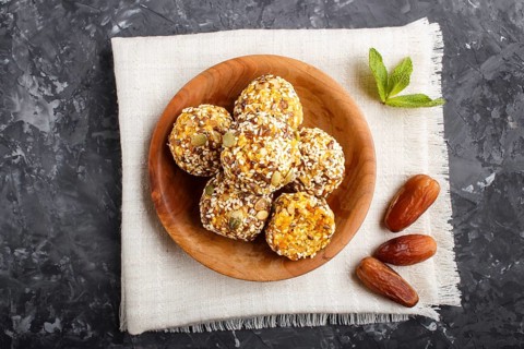 Energy ball cakes with dried apricots, sesame, linen, walnuts and dates with green mint leaves in a