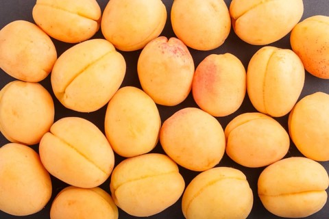 Apricots pattern on black background, top view, flat lay