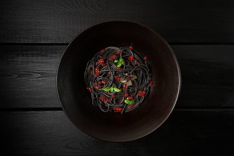 Black spaghetti with red caviar, pasta, on a black background, top view, no people
