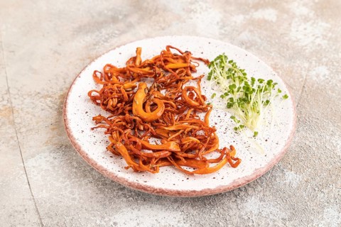 Fried Cordyceps militaris mushrooms on brown concrete background with microgreen, herbs and spices.