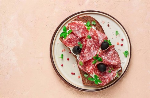Sandwich, grain bread, with cream cheese and salami, black olives, micro-greens, top view,