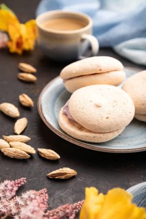 Meringues cakes with cup of coffee on a black concrete background and blue linen textile. Side