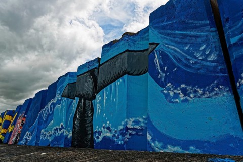 Colourful mural by the sea with a large whale under a cloudy sky, small town of Vila Franca do