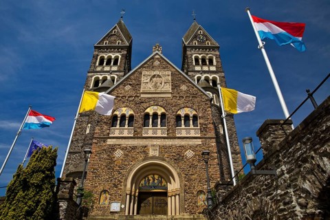 Roman Catholic parish church in Clerf with church flag and Luxembourg flag, Duchy of Luxembourg