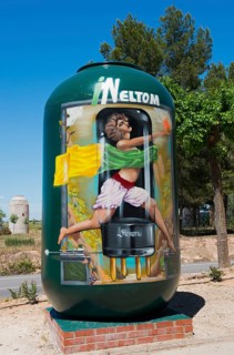 Großer grüner Behälter mit bemaltem Bild eines Menschen an einer Landstraße, Ermita y museo Virgen