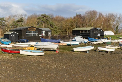 Fishing sheds and boats dinghies on trailers, Riverside tearoom, Orford, Suffolk, England, UK